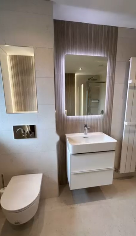 Neutral family bathroom with textured feature panel, backlit mirror and wall-hung vanity