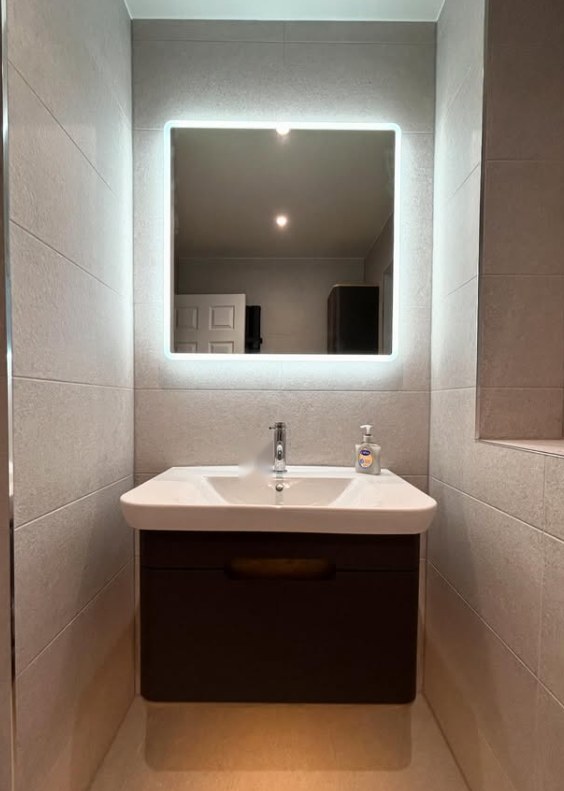 Compact en-suite with halo-lit square mirror and dark floating vanity