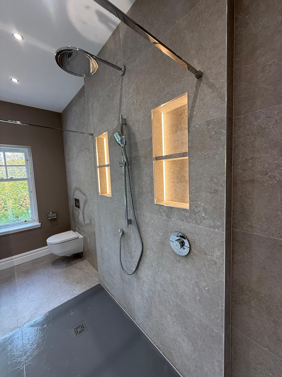 Walk-in shower with stone-effect tiling and twin backlit niches