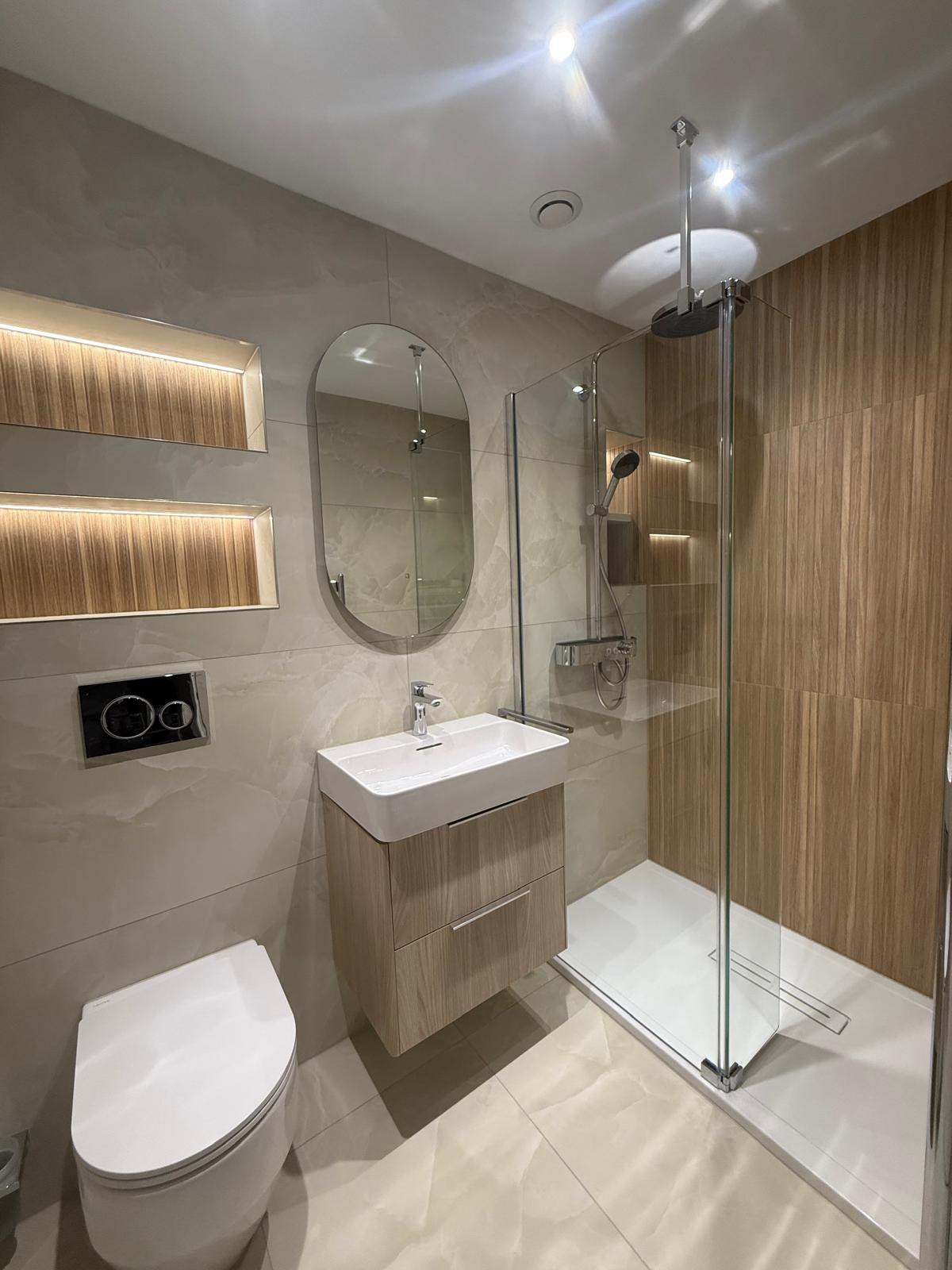 Bathroom with walk-in shower, wood-slat feature wall, twin illuminated niches and oval backlit mirror