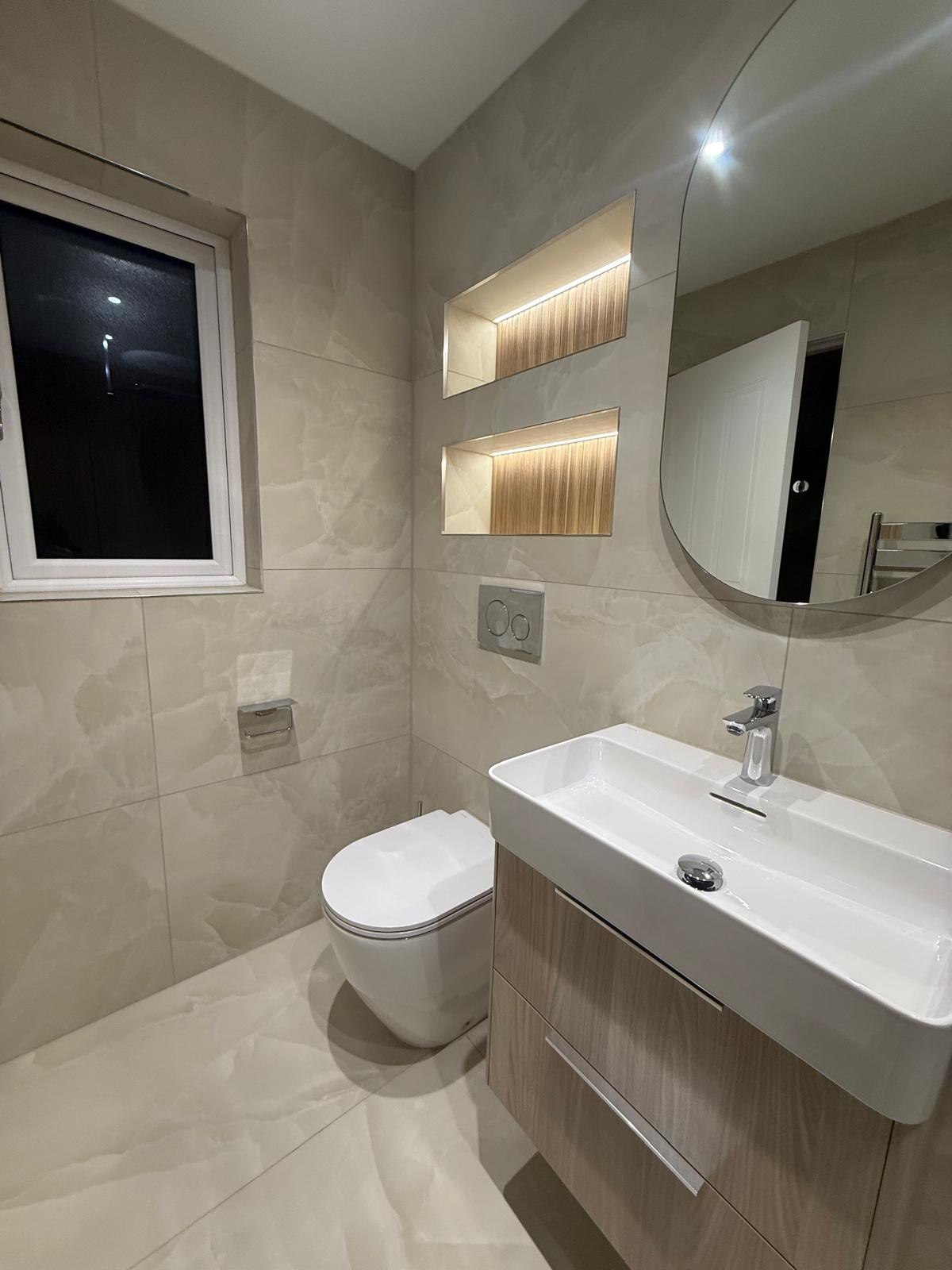 Floating timber vanity with white basin beneath illuminated storage niches